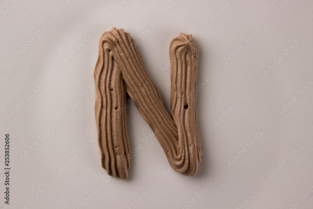Sweet chocolate letter N drawn with whipped cream on a white plate Sweet chocolate letter N drawn with whipped cream on a white plate