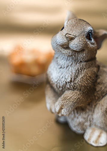 Fototapeta Naklejka Na Ścianę i Meble -  Smiling bunny in front of a bosl of cheese cubes on a gold background