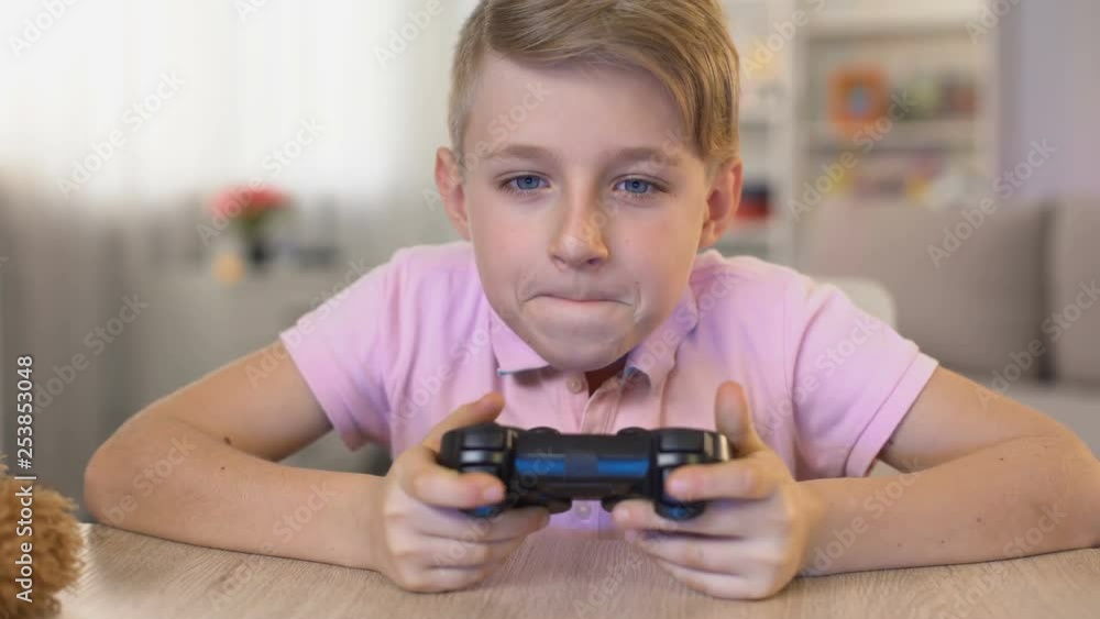 Excited male kid taking joystick from table, playing video game, entertainment Excited male kid taking joystick from table, playing video game, entertainment