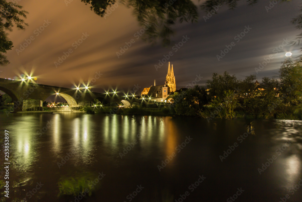 A night long exposure of the cathedral Dom St Peter with an old stone bridge along the Danube