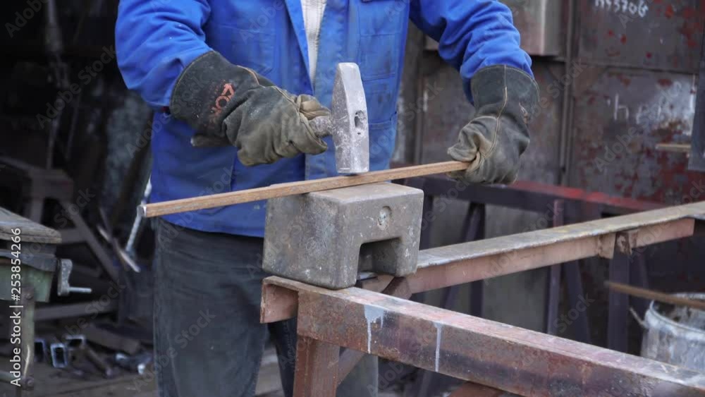 A blacksmith hammering metal construction on the anvil A blacksmith hammering metal construction on the anvil