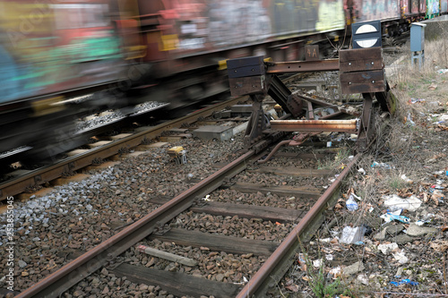 Müll am Bahngleis und vorbeifahrender Zug mit Graffiti - Stockfoto