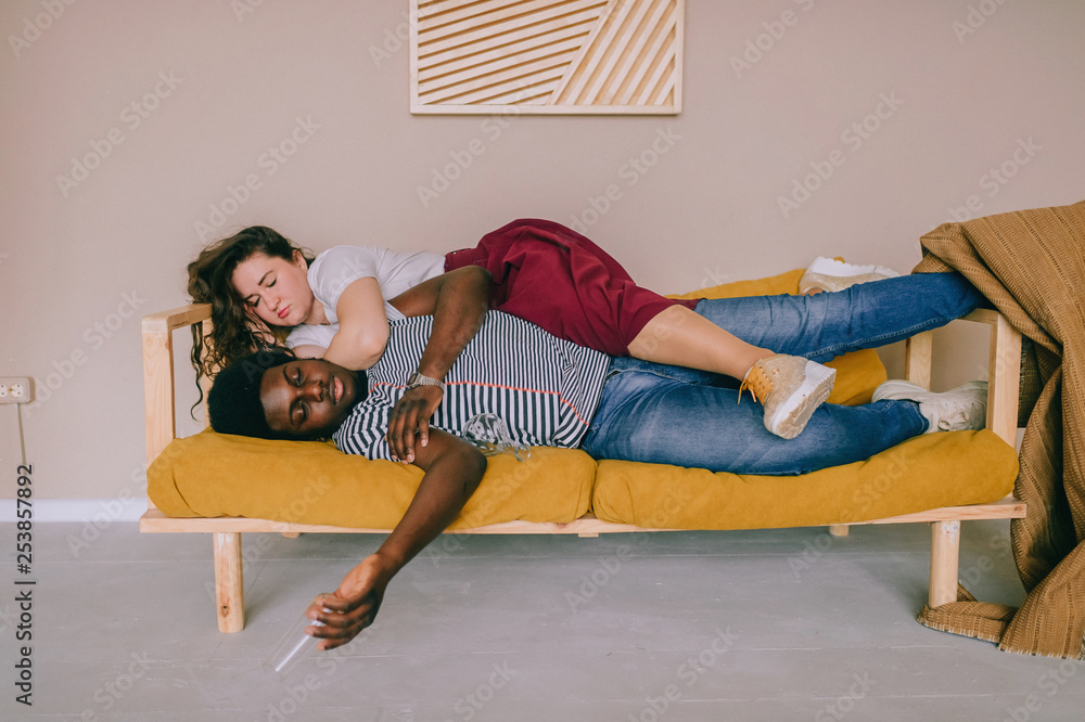 Funny blurred soft focus portrait of odd interracial drunk couple sleeping  on bed at home after