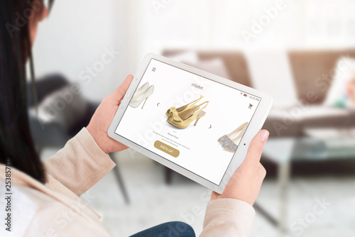 Woman shopping online with tablet. Modern commerce web site interface with shoes.