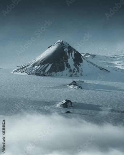 Large black hill in the center of a flat snowy landscape photo