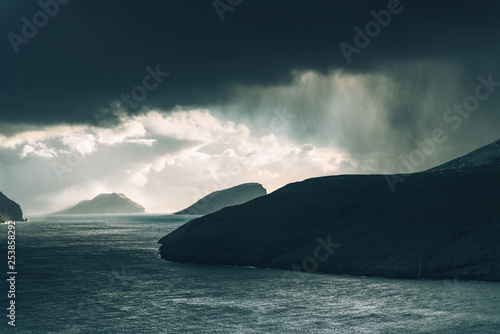 Rain falling from distant clouds over water in the Faroe Islands