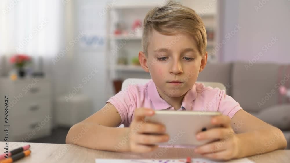 School boy playing smartphone game instead drawing, gadget addiction, hobby School boy playing smartphone game instead drawing, gadget addiction, hobby