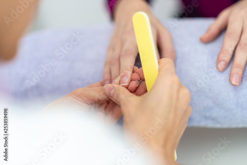 Closeup of manicurist holding a nail file checking a fingernail of a woman