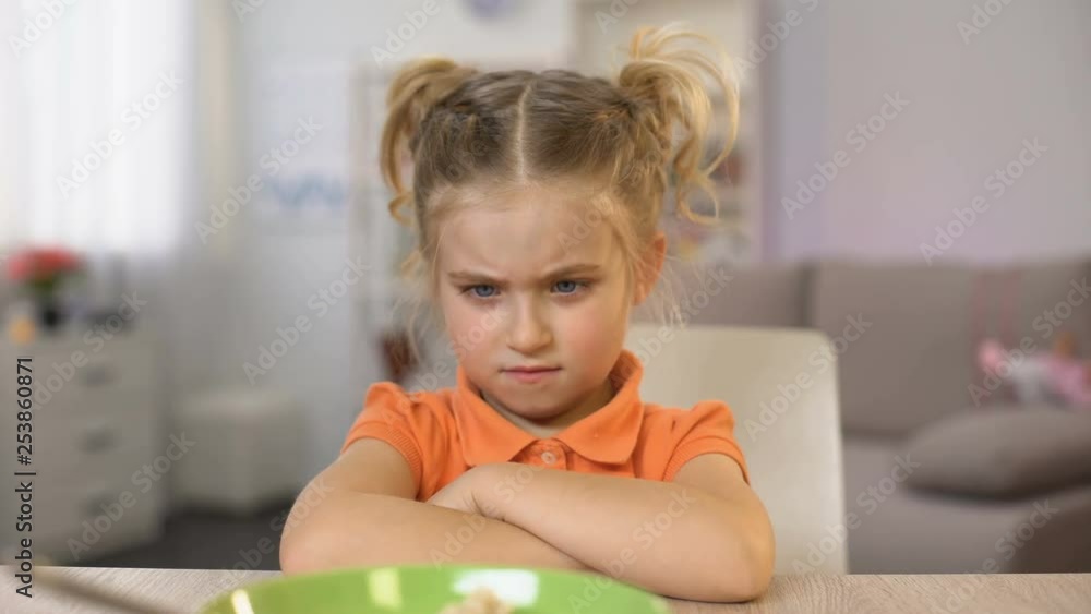 Girl refusing eat breakfast oatmeal, pushing bowl away, healthy child nutrition Girl refusing eat breakfast oatmeal, pushing bowl away, healthy child nutrition
