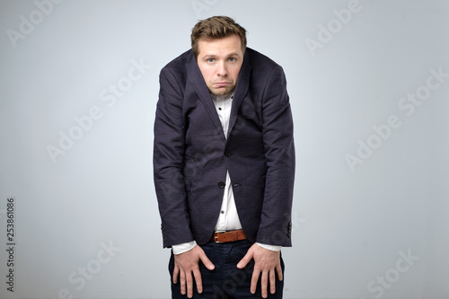 Young man in too big suit. He is offended and looking stressed. photo