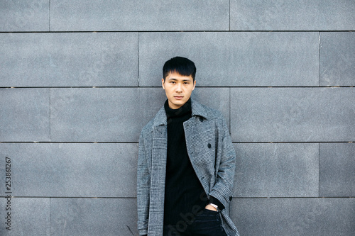 Portrait of stylish young man wearing black turtleneck pullover and grey coat photo