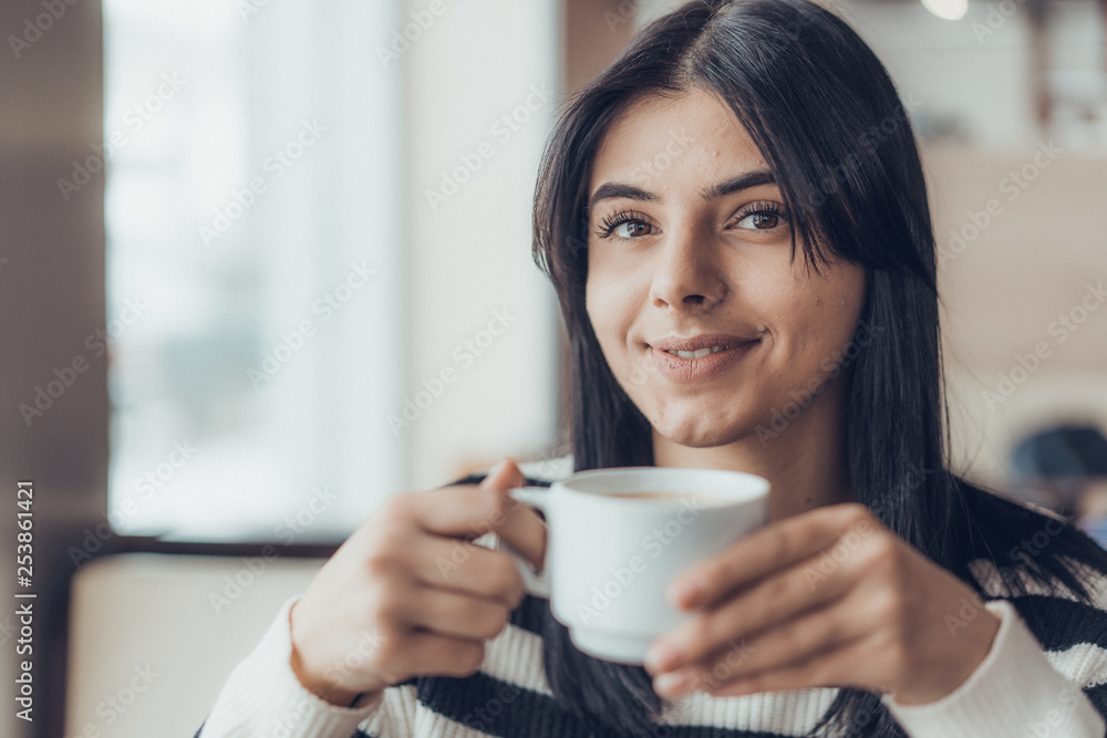 Beautiful caucasian girl in casual clothes with coffe in hands smiling while sitting in cafe. success. Beautiful caucasian girl in casual clothes with coffe in hands smiling while sitting in cafe. success.