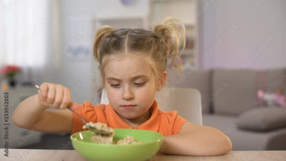 Mother putting table bowl with healthy oatmeal, daughter refusing eat porridge Mother putting table bowl with healthy oatmeal, daughter refusing eat porridge