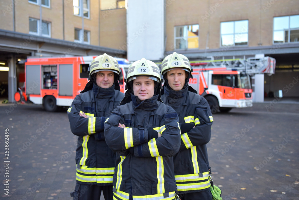 Portrait of three confident firefighters standing on yard in front of fire engine Portrait of three confident firefighters standing on yard in front of fire engine