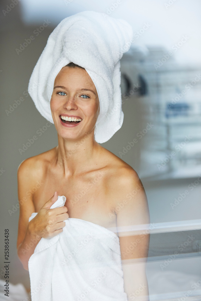 Portrait of happy young woman behind windowpane wrapped in towels Portrait of happy young woman behind windowpane wrapped in towels