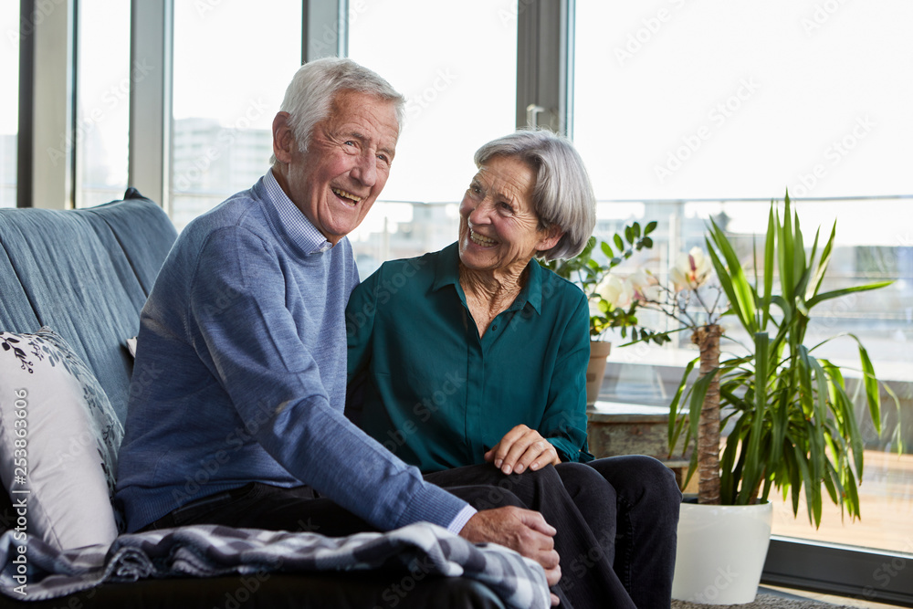 Laughing senior couple sitting together on couch Laughing senior couple sitting together on couch