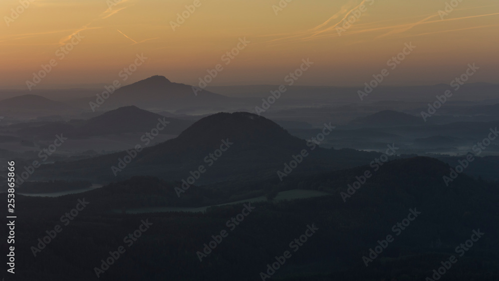 Landscape full of forest before sunrise with morning fog. Forest landscape where peaks of hills are above the fog.