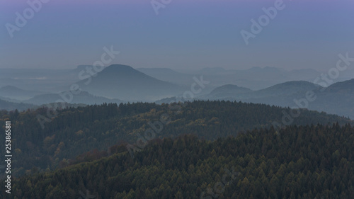 Landscape full of forest before sunrise with morning fog. Forest landscape where peaks of hills are above the fog.