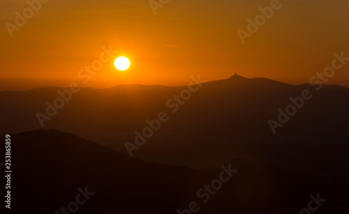 Amazing sunrise above mountain ridge with hill "Jested". The orange sun near the horizon. Beautiful view on sunrise landscape.