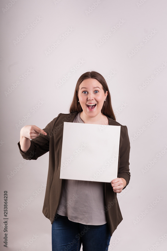 Young woman holding blank white board pointing at sign great smile Young woman holding blank white board pointing at sign great smile