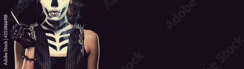 Woman with skeleton face art smoking over black background horizontal image