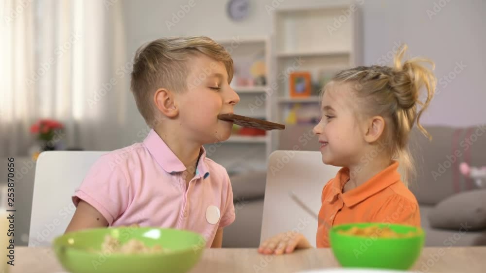 Male and female kids eating chocolate together, brother sharing sweets sister Male and female kids eating chocolate together, brother sharing sweets sister