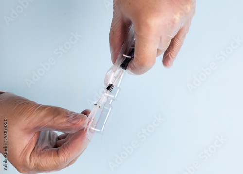 A male hand in a transparent medical nitrile glove holds a small syringe with medicine with a thin needle for subcutaneous administration. The concept of medicine, prevention of thrombophilia. IVF