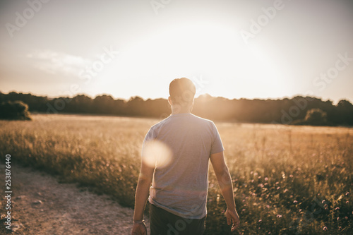 Mann wandert durch ein Feld im Sommer im Gegenlicht