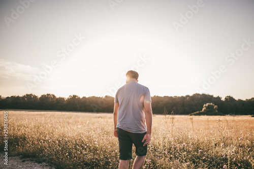 Mann wandert durch ein Feld im Sommer im Gegenlicht