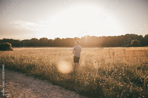 Mann wandert durch ein Feld im Sommer im Gegenlicht