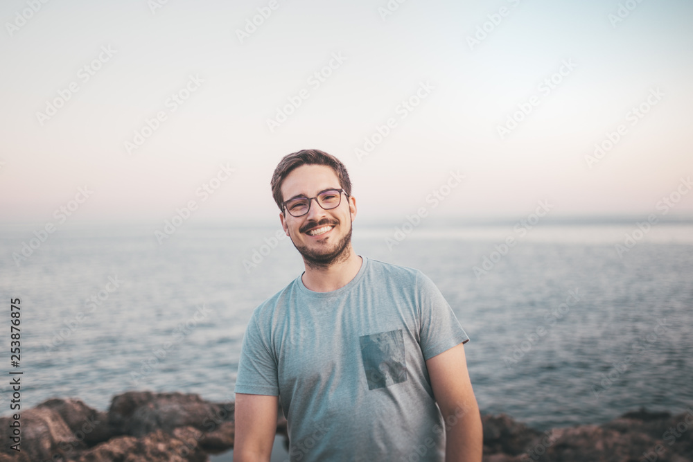 Mann mit Brille lächelt beim Urlaub am Strand 