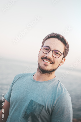 Mann mit Brille lächelt in die Kamera am Strand