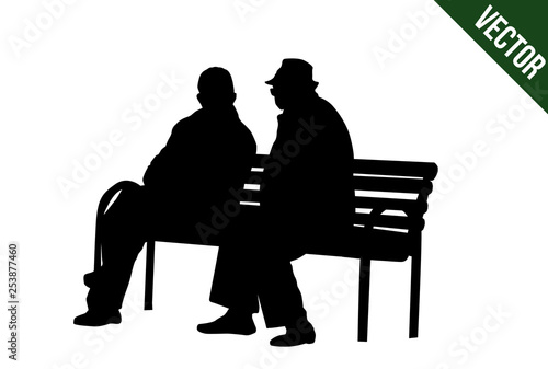 Two elderly people silhouettes sitting on a park bench