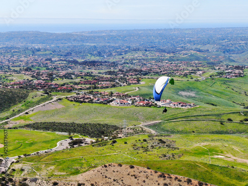 Para-glider over the top of the mountain during summer sunny day. Para-glider on the para-plane, strops -soaring flight moment flying over Black Mountain in San Diego, California. USA. photo