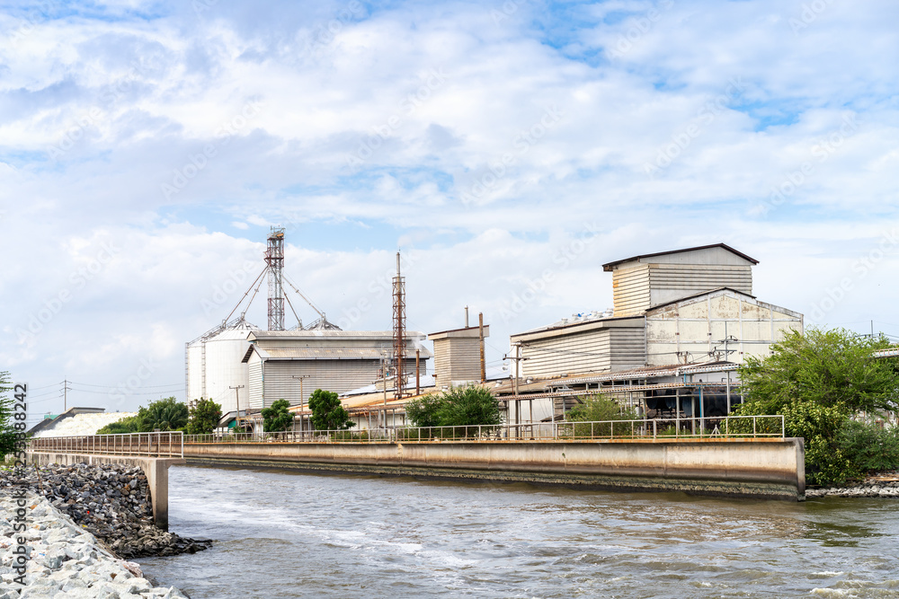 large industrial factory building side canal and aqueduct water bridge across road for drainage to sea with beautiful blue sky at bright day (in thailand) large industrial factory building side canal and aqueduct water bridge across road for drainage to sea with beautiful blue sky at bright day (in thailand)