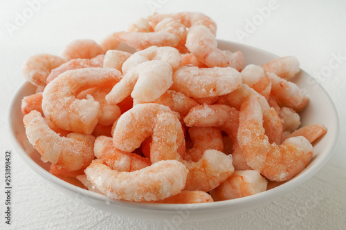 Fresh frozen shrimps on a white plate in white background, close up