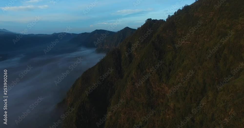 Drone shot of the Bromo mountains, with a sea of clouds at the bottom during sunrise Drone shot of the Bromo mountains, with a sea of clouds at the bottom during sunrise