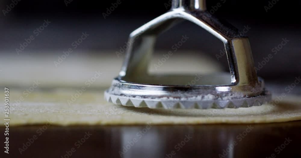Gorgeous close up of a traditional silver pasta stamping tool making shapes in a sheet of fresh pasta. Beautiful light and high quality. Gorgeous close up of a traditional silver pasta stamping tool making shapes in a sheet of fresh pasta. Beautiful light and high quality.