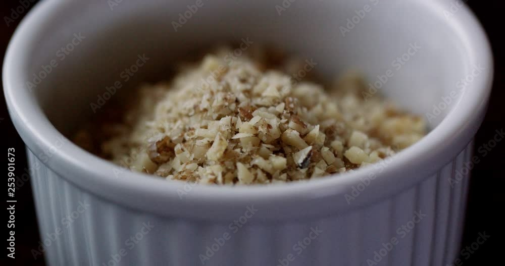 Chopped nuts in a white ceramic ramekin shot up close. Hand moves in and picks up ramekin. Beautiful light and high quality. Chopped nuts in a white ceramic ramekin shot up close. Hand moves in and picks up ramekin. Beautiful light and high quality.