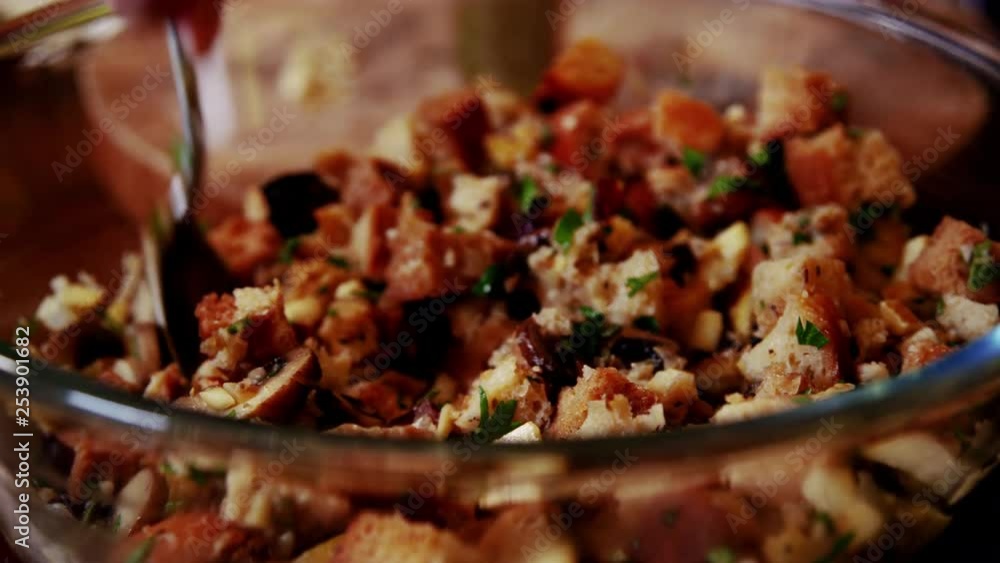 Up close shot of stuffing ingredients being stirred together in a glass bowl before cooking. Great details of bread, cranberries, mushrooms, fresh herbs. In 4K. Up close shot of stuffing ingredients being stirred together in a glass bowl before cooking. Great details of bread, cranberries, mushrooms, fresh herbs. In 4K.