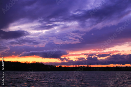 Dark sky above the water had gray and colorful clouds. Sunset at the approach of a rainstorm