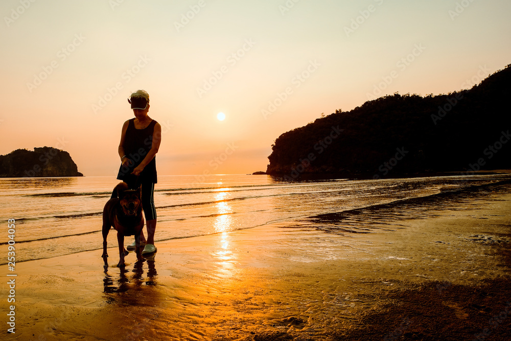 Senior Woman and dog on beach at sunrise Senior Woman and dog on beach at sunrise