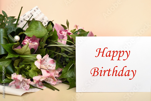 Bouquet of flowers and greeting card with Happy Birthday message. Selective focus. 