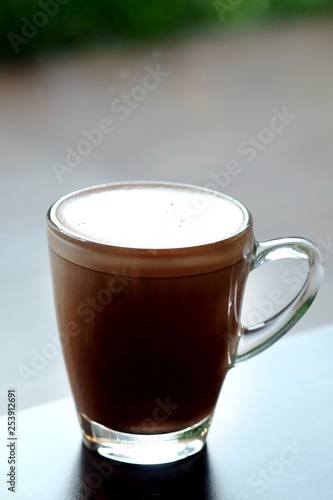 Hot chocolate or cocoa in clear glass cup on wood table in a restaurant with space for write wording, delicious antioxidant rich beverage that contain many health useful or health benefit for everyone