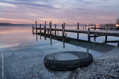 Magnificent sunset abandoned tire, wooden Pier on the lake. A tranquil sunset over a Varna lake. photo