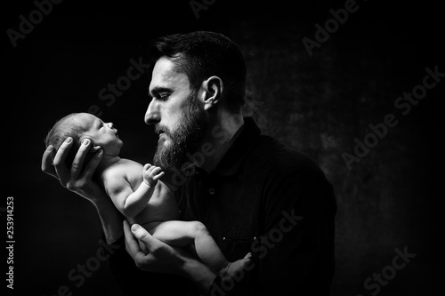 Portrait of happy father with little baby on dark background