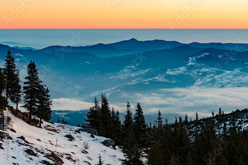 Mountain landscape with winter fog at sunse of Ceahlau, Romaniat