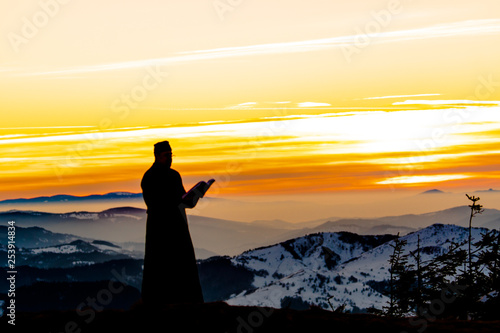Priest silhoute reading in the sunset light  Romania