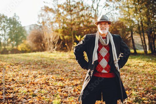 Handsome grandfather in a autumn park. Old man in a gray jacket and hat.