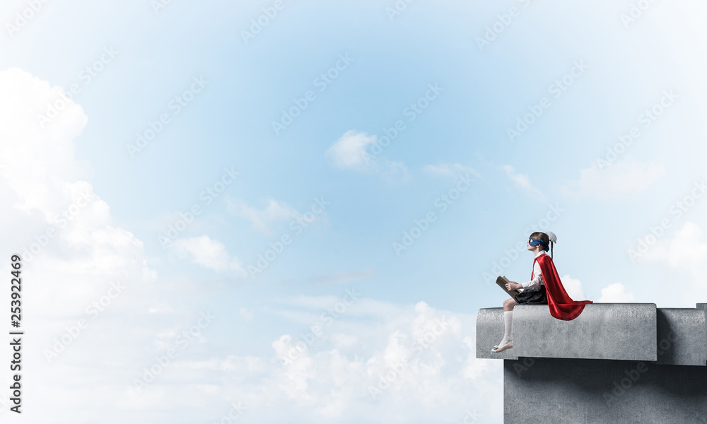 Girl power concept with cute kid guardian against cloudscape background . Mixed media Girl power concept with cute kid guardian against cloudscape background . Mixed media